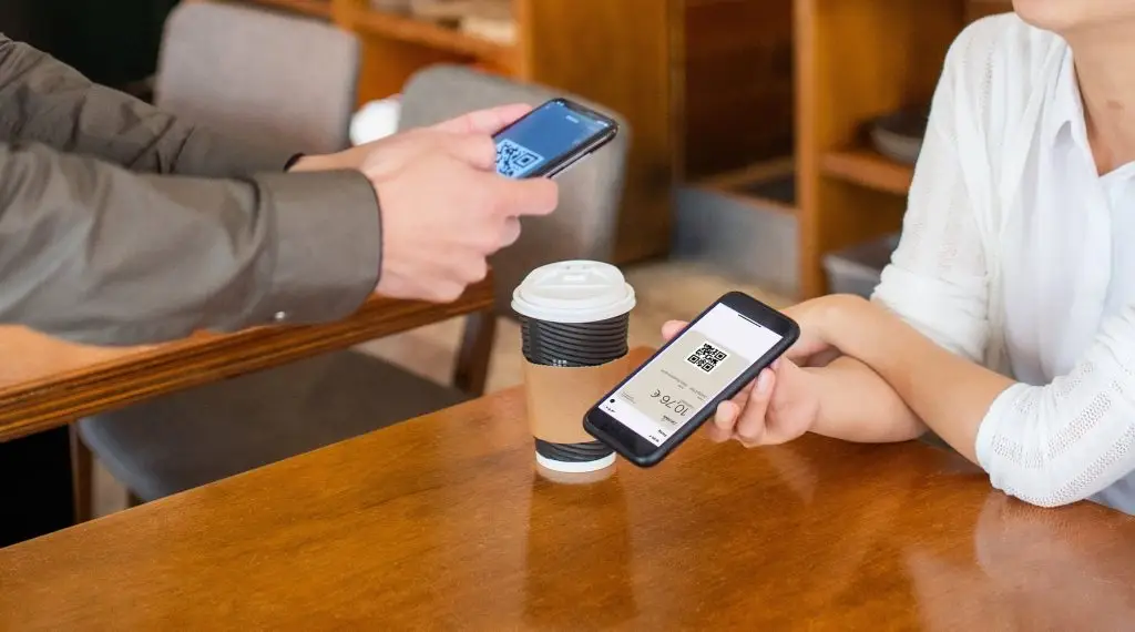 Homme et femme avec smartphone, café et qrcode