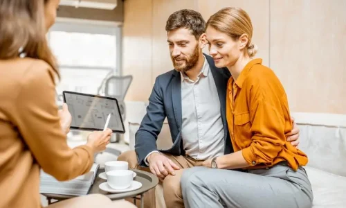 Une vendeuse montre une tablette à un couple souriant